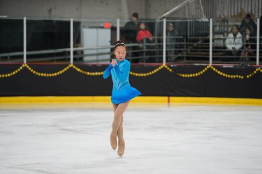 Mosinee, Wisconsin ABD - 26 Şubat 2021: Güzel mavi elbiseli genç Asyalı kadın porsuk eyaleti buz pateni yarışmasına katıldı.