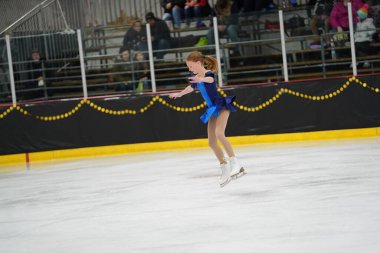 Mosinee, Wisconsin ABD - 26 Şubat 2021: Porsuk Eyaleti buz pateni yarışmasına mavi elbiseli genç bir kadın katıldı.