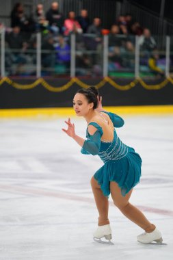 Mosinee, Wisconsin ABD - 26 Şubat 2021: Porsuk eyaleti buz pateni yarışmasına katılan turkuaz elbiseli yetişkin kadın