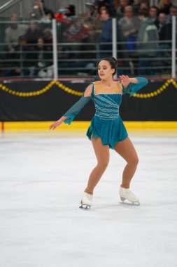 Mosinee, Wisconsin ABD - 26 Şubat 2021: Porsuk eyaleti buz pateni yarışmasına katılan turkuaz elbiseli yetişkin kadın