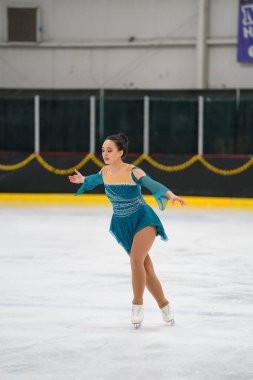 Mosinee, Wisconsin ABD - 26 Şubat 2021: Porsuk eyaleti buz pateni yarışmasına katılan turkuaz elbiseli yetişkin kadın