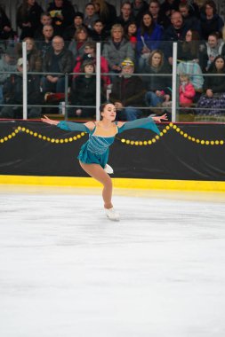 Mosinee, Wisconsin ABD - 26 Şubat 2021: Porsuk eyaleti buz pateni yarışmasına katılan turkuaz elbiseli yetişkin kadın