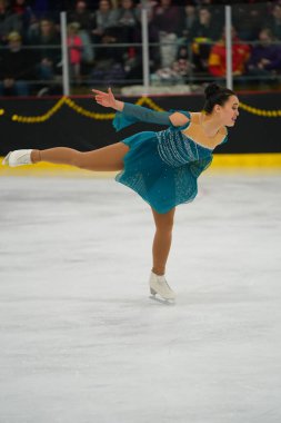 Mosinee, Wisconsin ABD - 26 Şubat 2021: Porsuk eyaleti buz pateni yarışmasına katılan turkuaz elbiseli yetişkin kadın