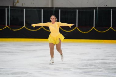 Mosinee, Wisconsin ABD - 26 Şubat 2021: Porsuk Eyaleti buz pateni yarışmasına katılan sarı elbiseli genç bir kadın