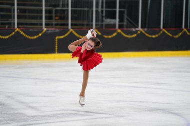 Mosinee, Wisconsin ABD - 26 Şubat 2021: Porsuk eyaleti buz pateni yarışmasına katılan kırmızı elbiseli genç bayan