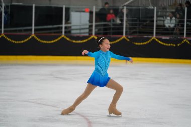 Mosinee, Wisconsin ABD - 26 Şubat 2021: Güzel mavi elbiseli genç Asyalı kadın porsuk eyaleti buz pateni yarışmasına katıldı