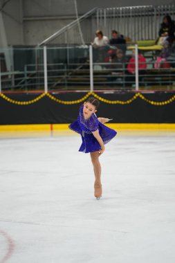 Mosinee, Wisconsin ABD - 26 Şubat 2021: Porsuk Eyaleti buz pateni yarışmasına mavi elbiseli genç bir kadın katıldı