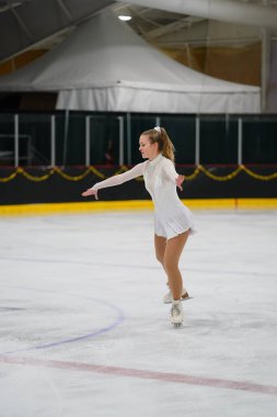 Mosinee, Wisconsin ABD - 26 Şubat 2021: Porsuk eyaleti buz pateni yarışmasına güzel beyaz elbiseli yetişkin kadın katıldı