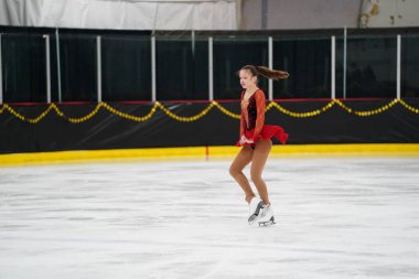 Mosinee, Wisconsin ABD - 26 Şubat 2021: Porsuk Eyaleti buz pateni yarışmasına katılan kırmızı elbiseli genç bir kadın.