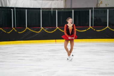 Mosinee, Wisconsin ABD - 26 Şubat 2021: Porsuk Eyaleti buz pateni yarışmasına katılan kırmızı elbiseli genç bir kadın.