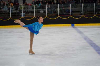 Mosinee, Wisconsin ABD - 26 Şubat 2021: Güzel mavi elbiseli Asyalı yetişkin kadın porsuk eyaleti buz pateni yarışmasına katıldı