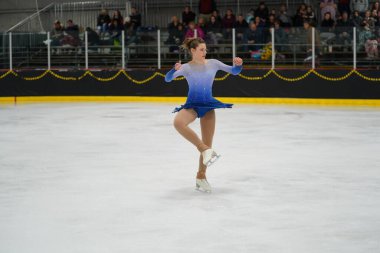 Mosinee, Wisconsin ABD - 26 Şubat 2021: Porsuk Eyaleti buz pateni yarışmasına mavi elbiseli genç bir kadın katıldı