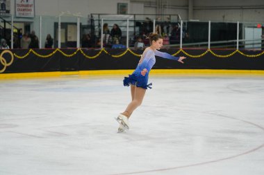 Mosinee, Wisconsin ABD - 26 Şubat 2021: Porsuk Eyaleti buz pateni yarışmasına mavi elbiseli genç bir kadın katıldı