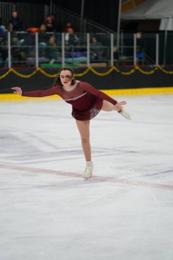 Mosinee, Wisconsin ABD - 26 Şubat 2021: Porsuk Eyaleti buz pateni yarışmasına katılan kırmızı elbiseli genç bir kadın.