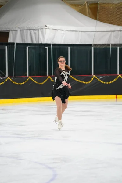 米国ウィスコンシン州モシニア 2021年2月26日 美しい黒いドレスの若いティーンエイジャーの女性が より悪い州の冬のゲームアイススケート競技に参加しました — ストック写真