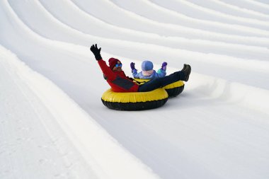 Kewaskum, Wisconsin / USA - December 24th, 2019: Many family members came out to enjoy themselves snow tubing on the day before Christmas at Sunburst Winter Sports Park for Santa Slalom event.   clipart