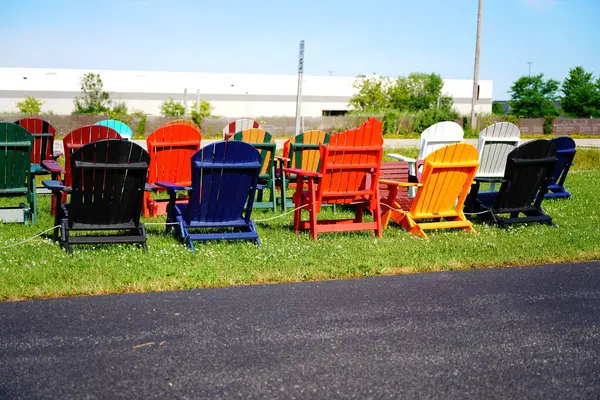 Colorful wooden lawn chairs set up outside to be sold in the fond du lac, wisconsin area.