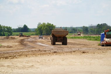 Fond du Lac, Wisconsin / USA - 14 Temmuz 2020: Caterpillar 735 inşaat atık kamyonları arsayı inşa etmek için toprak madde taşıyor.