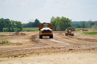 Fond du Lac, Wisconsin / USA - 14 Temmuz 2020: Caterpillar 735 inşaat atık kamyonları arsayı inşa etmek için toprak madde taşıyor.