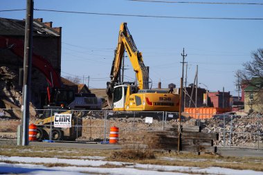 Racine, Wisconsin / USA - February 21st, 2020: Volvo, Liebherr, and Link-Belt excavators being used to demolishing an old building at a deconstruction site. clipart