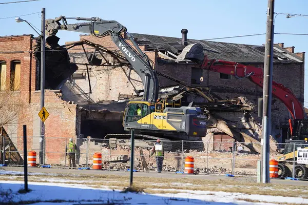 stock image Racine, Wisconsin / USA - February 21st, 2020: Volvo, Liebherr, and Link-Belt excavators being used to demolishing an old building at a deconstruction site.