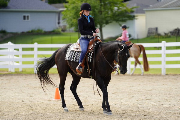 Fond du Lac, Wisconsin / USA - July 17th, 2019: Young girl riding around on her horse on a public horse ranch field in Fond du Lac, Wisconsin
