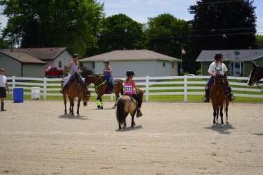 Fond du Lac, Wisconsin / USA - July 17th, 2019: Young girls riding around on horses on a public horse ranch field in Fond du Lac, Wisconsin clipart
