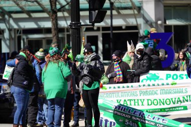 Milwaukee, Wisconsin ABD - 12 Mart 2022: Shamrock kulübü üyeleri Aziz Patrick günü için giyindiler ve geçit töreni için pankart taşıdılar.