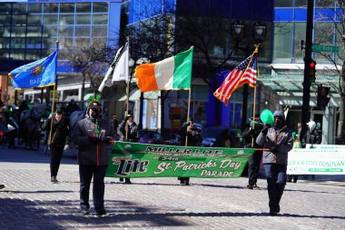Milwaukee, Wisconsin ABD - 12 Mart 2022: Shamrock kulübü üyeleri Aziz Patrick günü için giyindiler ve geçit töreni için pankart taşıdılar.