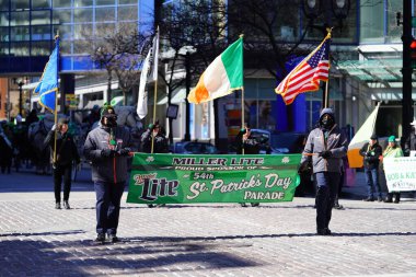 Milwaukee, Wisconsin ABD - 12 Mart 2022: Shamrock kulübü üyeleri Aziz Patrick günü için giyindiler ve geçit töreni için pankart taşıdılar.