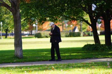 Parkta cep telefonu olan genç bir adam.