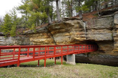 İnsan yapımı kırmızı bir köprü Wisconsin, Rockbridge 'deki Pier County Parkı' ndaki bir kaya tüneline çıkıyor..