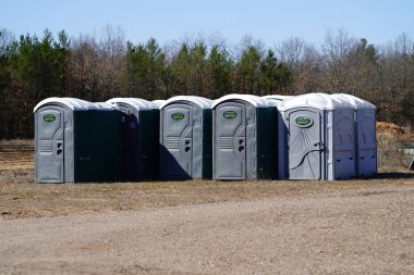 New Lisbon, Wisconsin USA - March 29th, 2024: Group of porta potties gathered together sitting outside waiting to be used. clipart