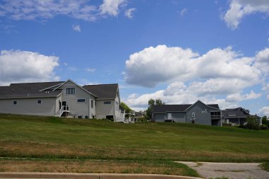 Güneşli bir günde mavi gökyüzünün altında yeşil çimlerle çevrili evlerin dikey görüntüsü.