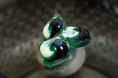 Çamaşır deterjanı sabun kapsülleri çamaşır makinesinin üstünde durur..