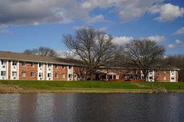 Mauston, Wisconsin ABD - 13 Nisan 2024: Bulutlu bir günde Brick 'in göl kenarındaki apartmanlarının manzarası.