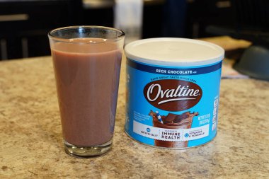 Fond du Lac, Wisconsin USA - 19 Mayıs 2024: Bir kutu Nestle Ovaltine zengin çikolatalı süt ve bir bardak süt mutfak tezgahında duruyor.