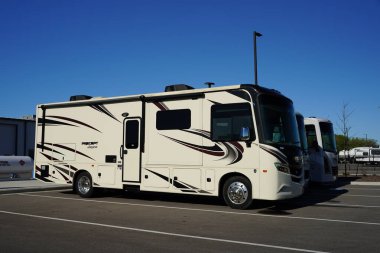 Oshkosh, Wisconsin USA - May 12th, 2024: Many different brands of campers and RVs sit parked at a dealership to be sold for the coming summer vacation. clipart