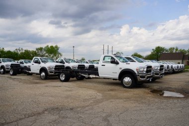 Burlington, Wisconsin USA - May 4th, 2024: A large collection of White Dodge Ram Trucks sit at a parking lot ready to be sold.