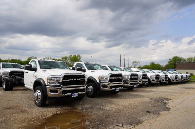 Burlington, Wisconsin USA - May 4th, 2024: A large collection of White Dodge Ram Trucks sit at a parking lot ready to be sold.