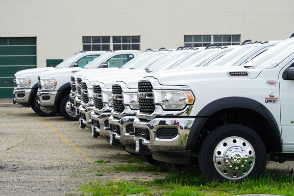 Burlington, Wisconsin USA - May 4th, 2024: A large collection of White Dodge Ram Trucks sit at a parking lot ready to be sold.