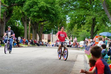 Appleton, Wisconsin ABD - 7 Haziran 2024: Birçok toplum üyesi, şehir merkezinde motosikletlilerin yürüdüğü Bayrak Günü geçit törenini izlemek için izleyici olmaya geldi..
