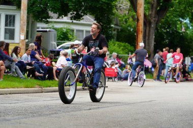 Appleton, Wisconsin ABD - 7 Haziran 2024: Birçok toplum üyesi, şehir merkezinde motosikletlilerin yürüdüğü Bayrak Günü geçit törenini izlemek için izleyici olmaya geldi..