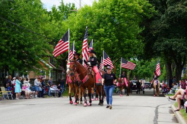 Appleton, Wisconsin ABD - 14 Haziran 2024: Bayrak Günü Geçidi boyunca Amerikan Bayraklarını taşıyan kadınlar.