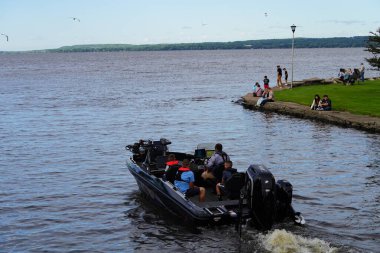 Fond du Lac, Wisconsin USA - 7 Haziran 2024: Mercury teknelerinde nehir ve göl kenarında seyahat eden aile fertleri.