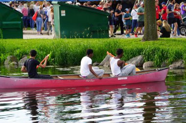 Fond du Lac, Wisconsin USA - 7 Haziran 2024: Erkekler ve dişiler göl ve bir halk parkındaki nehirlerde kürek çekmek için kano kullanıyorlar.