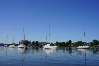 Oshkosh, Wisconsin ABD - 30 Mayıs 2024: Açık mavi gökyüzü boyunca bir gölde park etmiş yelkenliler.