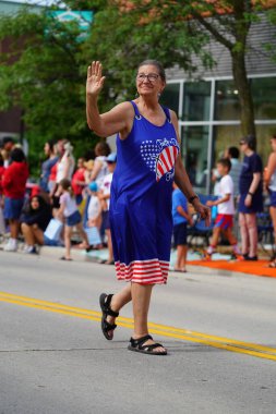 Sheboygan, Wisconsin ABD - 4 Temmuz 2024: Çocuklu aileler 4 Temmuz bayramı boyunca kaldırımlarda oturdu ve Özgürlük Festivali yürüyüşünü izledi.