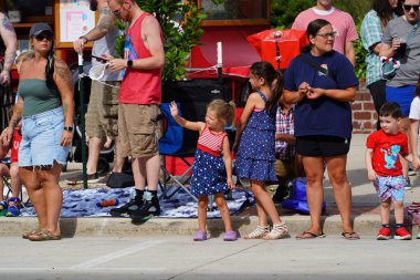 Sheboygan, Wisconsin ABD - 4 Temmuz 2024: Çocuklu aileler 4 Temmuz bayramı boyunca kaldırımlarda oturdu ve Özgürlük Festivali yürüyüşünü izledi.