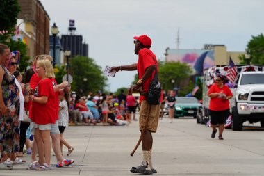 Sheboygan, Wisconsin ABD - 4 Temmuz 2024: Çocuklu aileler 4 Temmuz bayramı boyunca kaldırımlarda oturdu ve Özgürlük Festivali yürüyüşünü izledi.